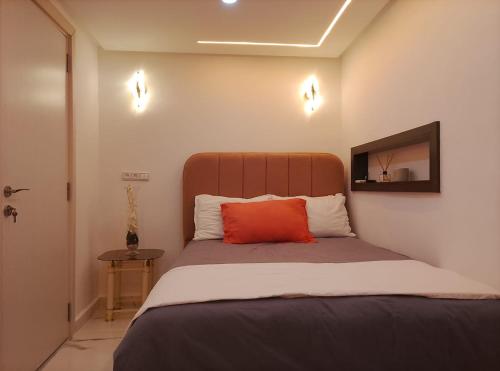 a bedroom with a bed with a orange pillow on it at Villa Harmonie - Suite Familiale avec Piscine in Khemisset