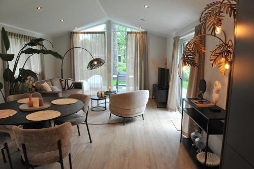 a living room with a couch and a table and chairs at Luxe Boshuisje Lodge Wildblick, adults only Haarle, Sallandse Heuvelrug in Haarle