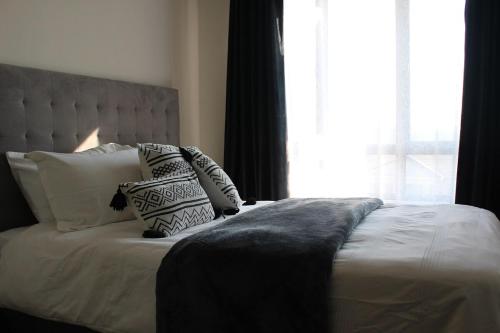 a bedroom with a bed with pillows and a window at First Gen Cedar Acres Fourways in Trevallyn