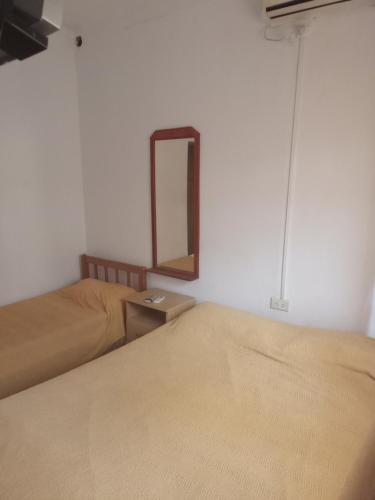 a bedroom with two beds and a mirror on the wall at Departamento Los Rosales in Villa Cura Brochero