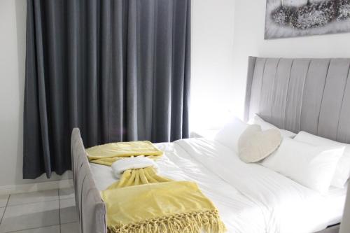 a bedroom with a white bed with yellow sheets at First Gen lagoon facing luxury apartment in Pretoria