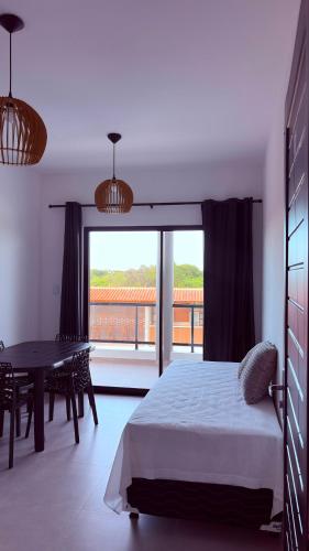 a bedroom with a bed and a table and a large window at Pousada Recanto dos Passaros in Aracati