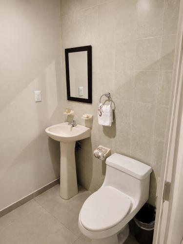 ein Badezimmer mit weißer Toilette und Waschbecken in der Unterkunft Hotel Tradicional Savaro SA de CV in Zihuatanejo