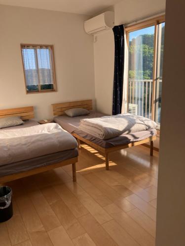 two beds in a room with a window at Ocean view Private Hotel in Shimoda