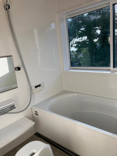 a bathroom with a tub and a toilet and a window at Ocean view Private Hotel in Shimoda