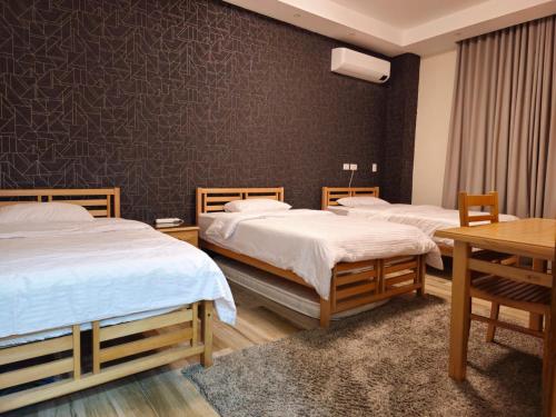 a bedroom with two beds and a table and a wall at Modern Hotel-Style Apartment in El Alamein