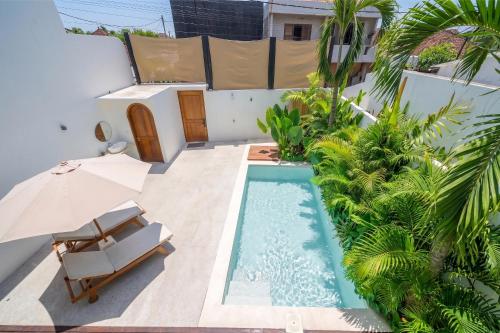 an outdoor swimming pool with a chair and an umbrella at Darina Villa - Private Rooftop Escape with Pool Close to Beach in Badung