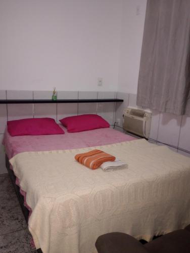 a bed with two pink pillows and a towel on it at Casa no centro - perto de tudo in Itaguaí