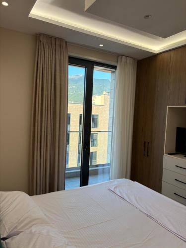 a bedroom with a bed and a large window at SL Apartment in Tirana