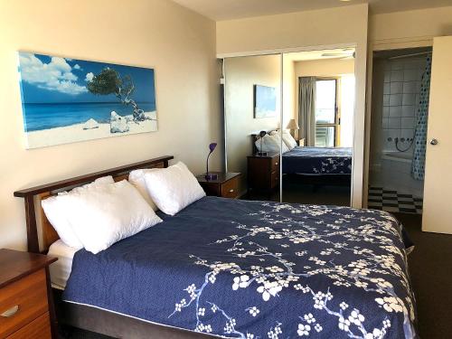 a bedroom with a bed with a blue comforter at Sea Eagles Unit 4 in Caloundra