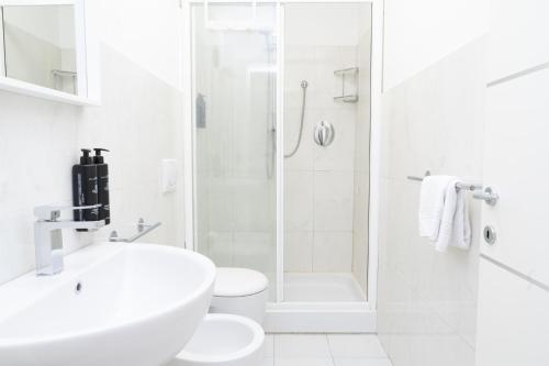 a white bathroom with a sink and a shower at Piazza Duomo Cathedral View in Brescia
