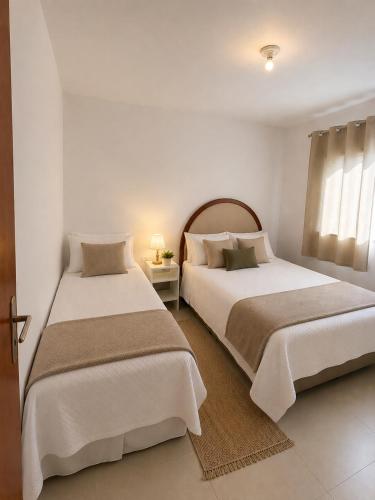 two beds in a room with white walls at Apartamento no Centro in Muriaé