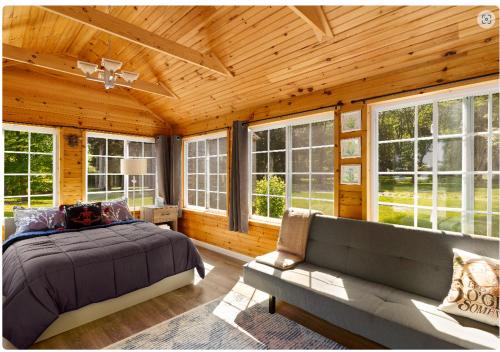 a bedroom with a bed and a couch and windows at Lakefront Guesthouse w Sunrise View Dock in Stonington