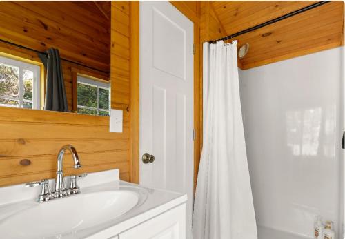 a bathroom with a sink and a white shower curtain at Lakefront Guesthouse w Sunrise View Dock in Stonington