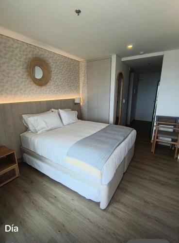 a bedroom with a large white bed and a mirror at Santa Martha-Apartment- Ocean view in Mirabel