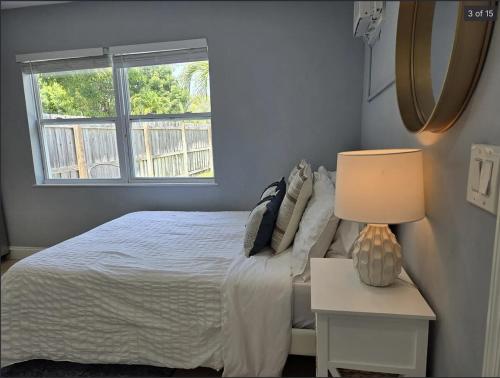 a bedroom with a bed with a lamp and a window at Hideaway Steps off Atlantic Ave - Private Studio in Delray Beach