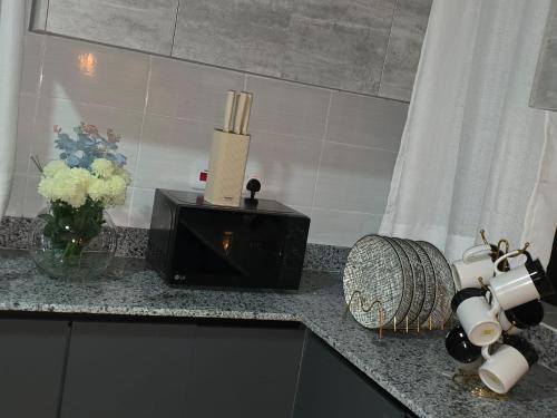 a kitchen counter with a microwave and flowers and a candle at Jaymorgan Villas 4 bedroomed in Nanyuki