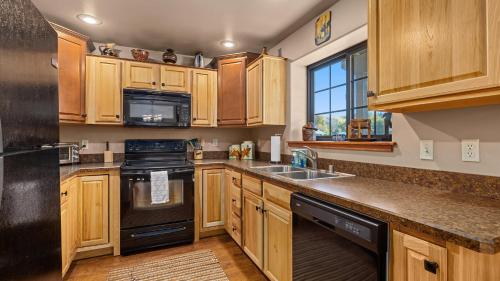 a kitchen with wooden cabinets and a black refrigerator at The Buckeye in Red Lodge