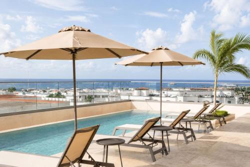 a pool with chairs and umbrellas on a roof at Hotel Indigo Playa del Carmen by IHG in Playa del Carmen
