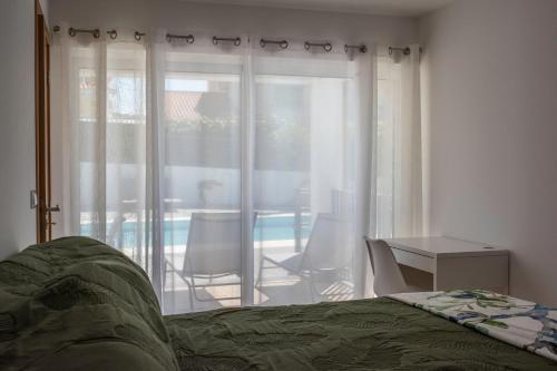 a bedroom with a bed and a view of a patio at Casa da Quinta da Azeitona 2 - Piscina privada e BBQ na Serra da Gardunha in Fundão