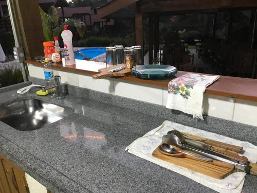 a kitchen counter with a sink and a wooden cutting board at POUSADA SuaCasita - 5 LAGOS in Mairiporã