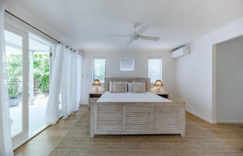 a white bedroom with a large bed and windows at Luxe Beach House at Sunshine in Sunshine Beach