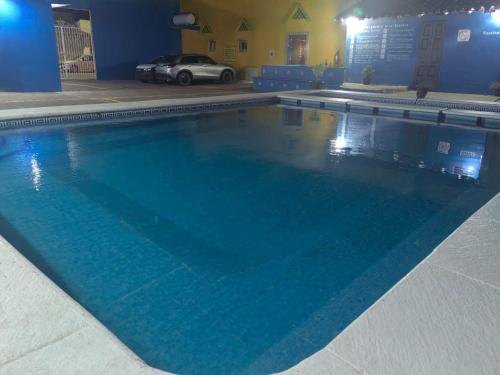 a large blue swimming pool with a car in the background at Hotel Tlacotalpan in Tlacotalpan