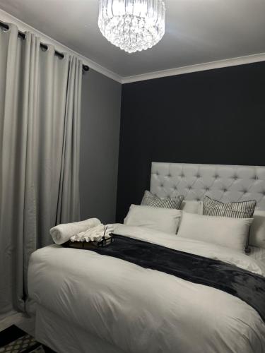 a bedroom with a large white bed with a chandelier at P Daisy in Rundu