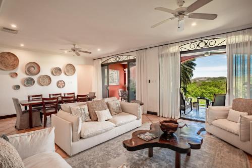 a living room with white furniture and a large window at Spacious 4BR Condo with Partial Ocean View - Bougainvillea - Reserva Conchal in Playa Conchal