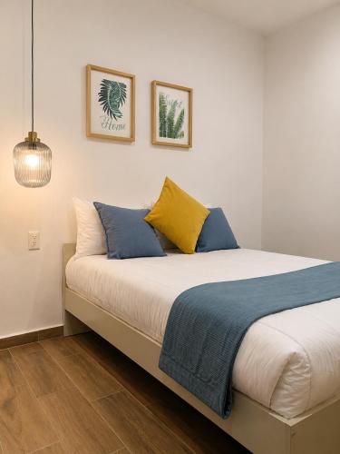 a bed with blue and yellow pillows in a room at Aloja Rentals Mexico in Mexico City