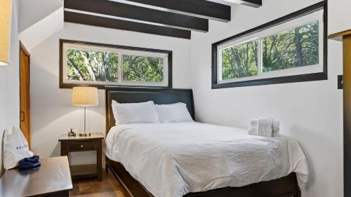 a bedroom with a bed and two windows at Emerald Overlook by AvantStay in Lake Arrowhead