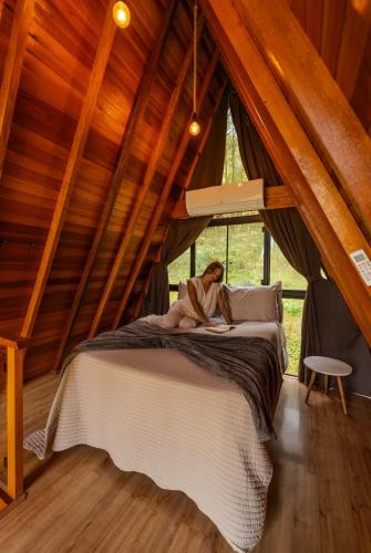 a woman laying on a bed in a room with wooden ceilings at Cabana com banheira in Gramado