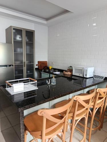 a kitchen with a black counter top and wooden chairs at Casa em Sorocaba para até 4 pessoas in Sorocaba
