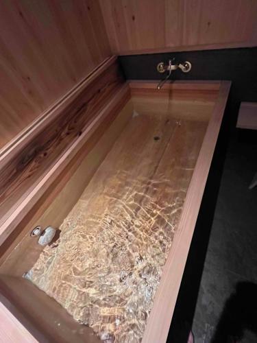 a bath tub with a shower in a room at 二食付き最高ランクの飛騨牛と地元野菜の炭火焼きディナーそしてプライベート檜風呂を体験できる個室古民家Resort Villaゲストハウスつぐや in Kurono