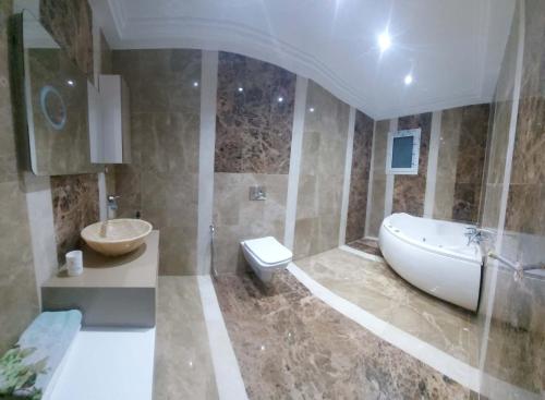 a bathroom with a tub and a toilet and a sink at Hammamet villa Bleu in Hammamet