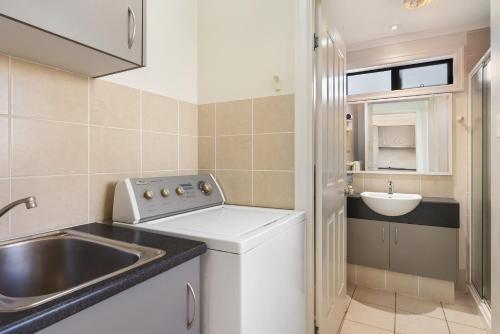 a small kitchen with a sink and a washing machine at Brisbane Gateway Resort in Rochedale