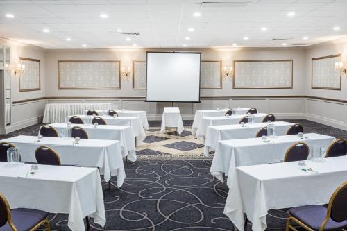 a room with white tables and chairs and a screen at Wyndham Garden Greensboro in Greensboro