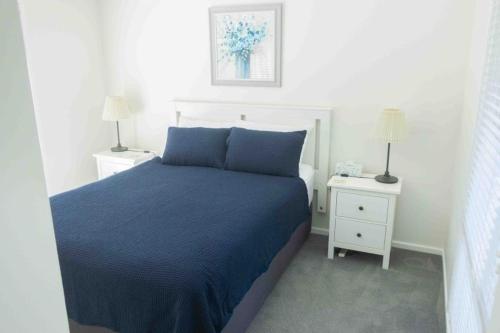 a bedroom with a blue bed and two night stands at Glistening Waters in Tathra