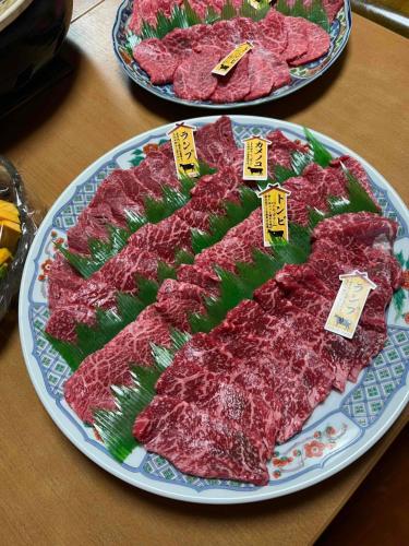 two plates of meat on a table with tags on them at 二食付き最高ランクの飛騨牛と地元野菜の炭火焼きディナーそしてプライベート檜風呂を体験できる個室古民家Resort Villaゲストハウスつぐや in Kurono
