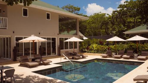 a pool with chairs and umbrellas next to a house at The Providence Hotel Boutique - Adults Only in San Andrés