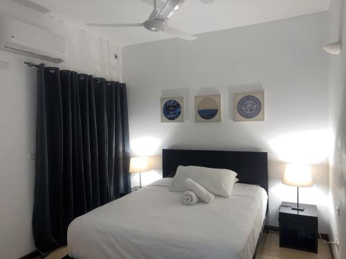 ein Schlafzimmer mit einem weißen Bett, zwei Lampen und zwei Ansteckern in der Unterkunft Don César in Las Terrenas