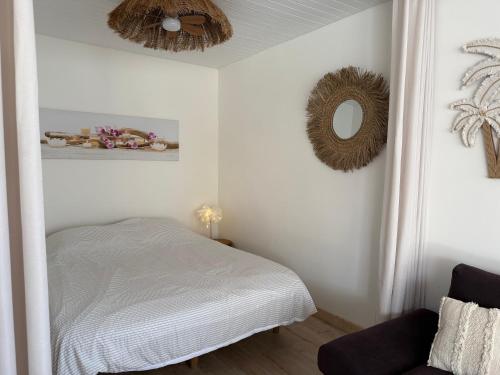 a white bedroom with a bed and a mirror at L Effet Mer Cocon climatisé avec terrasse et jardin privés Piscine in Audenge
