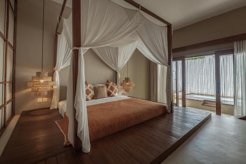 a bedroom with a bed with a canopy at YŪN Uluwatu in Uluwatu