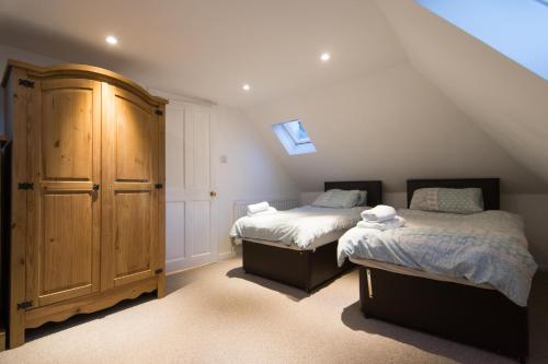 1 dormitorio en el ático con 2 camas y armario de madera en Blair Drummond Holiday Home, en Doune