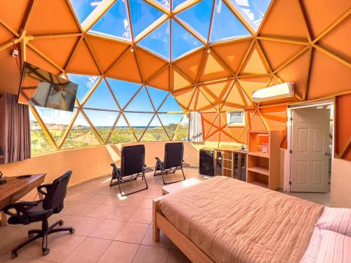 a bedroom with a large glass ceiling with a bed and chairs at Los Domecitos - Geodesic Dome Retreat in Los Barriles