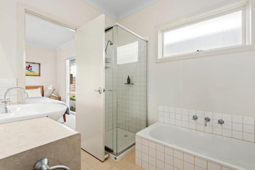 a bathroom with a shower and a tub and a sink at Kassandra in Point Lonsdale