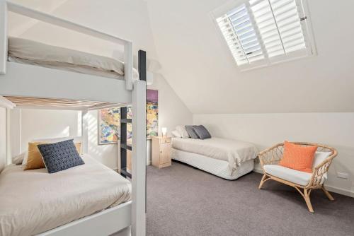 a bedroom with two bunk beds and a chair at Kassandra in Point Lonsdale