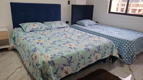 a bedroom with two beds with a blue and white comforter at Lindo apartamento en Villapinzon in Villapinzón