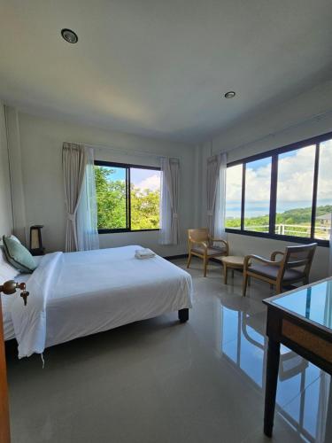 a bedroom with a bed and a desk and windows at Anda Sea view in Klong Muang Beach