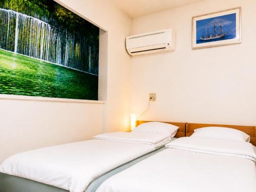 two beds in a room with a tv on the wall at Lee Ryokan Tokyo in Tokyo